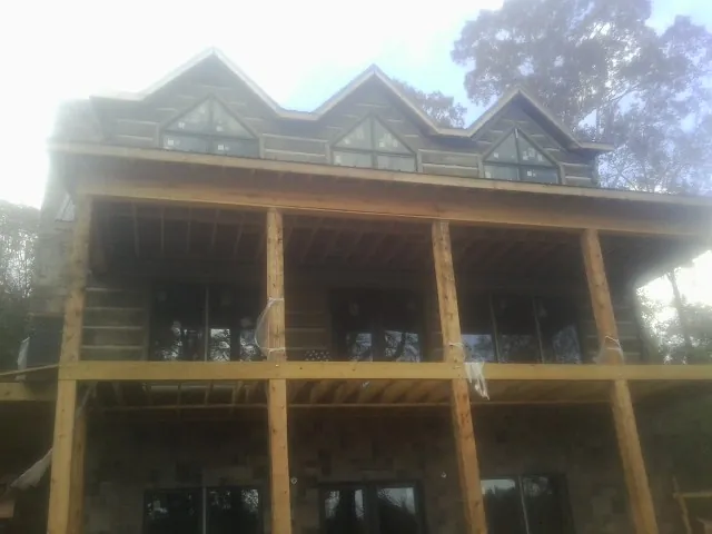 Dormers and porch framing on a large log home under construction — Roof Coating work by our crew in Round Hill