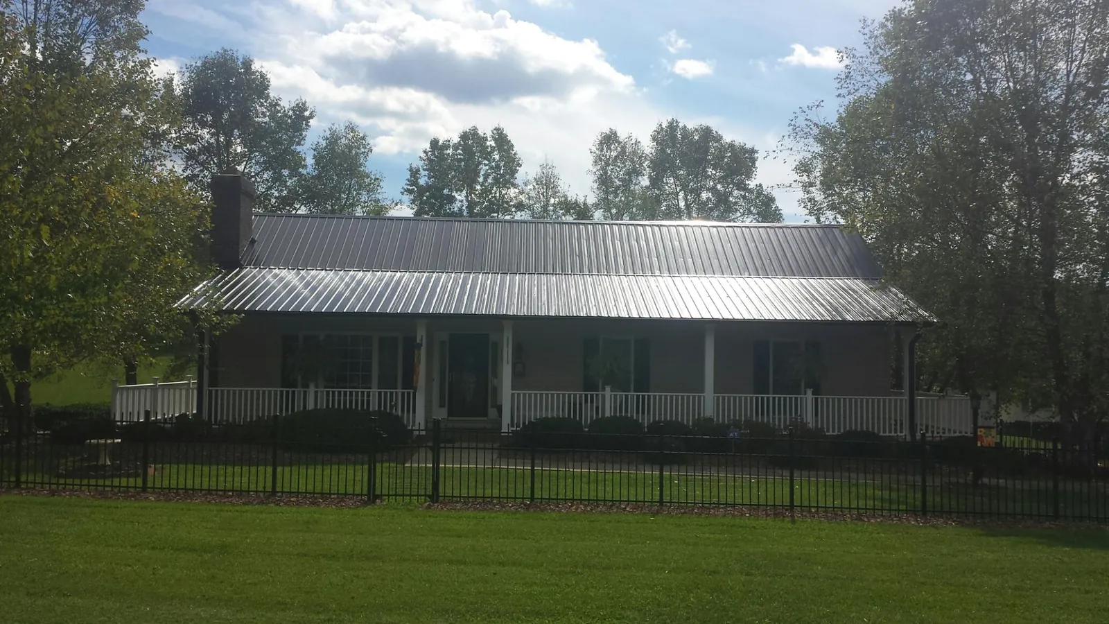 Gray metal roof on a brick ranch with a full width front porch — Gutter Guard Installation work by our crew in Round Hill